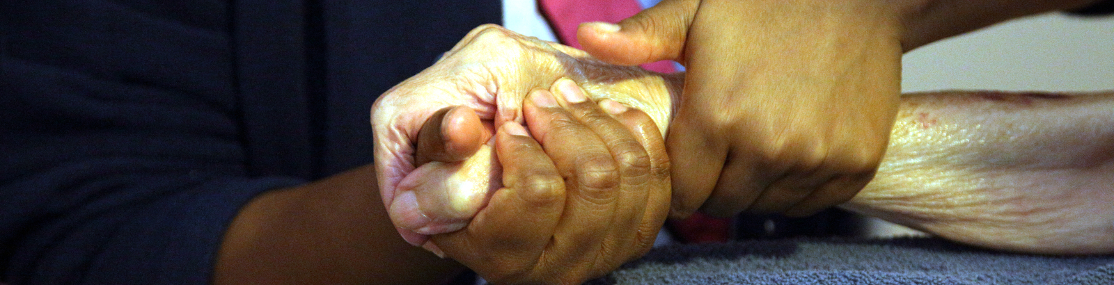 Une femme accompagne une personne âgée en lui tenant la main. Image pour article don sur succession